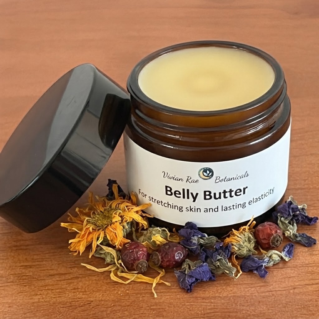 Open jar of Belly Butter with dried calendula flowers, violets and rose hips
