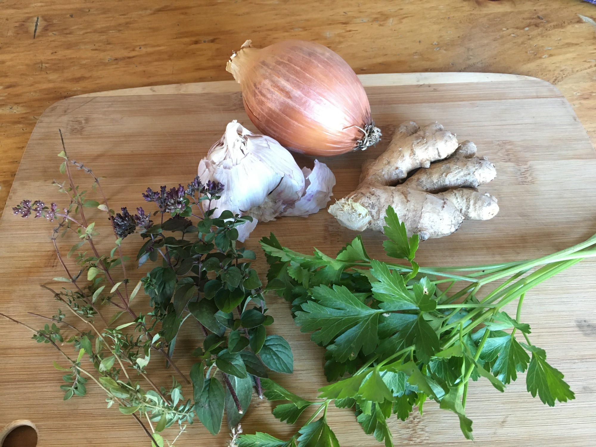 Onion, garlic, ginger root and fresh herbs on a cutting board