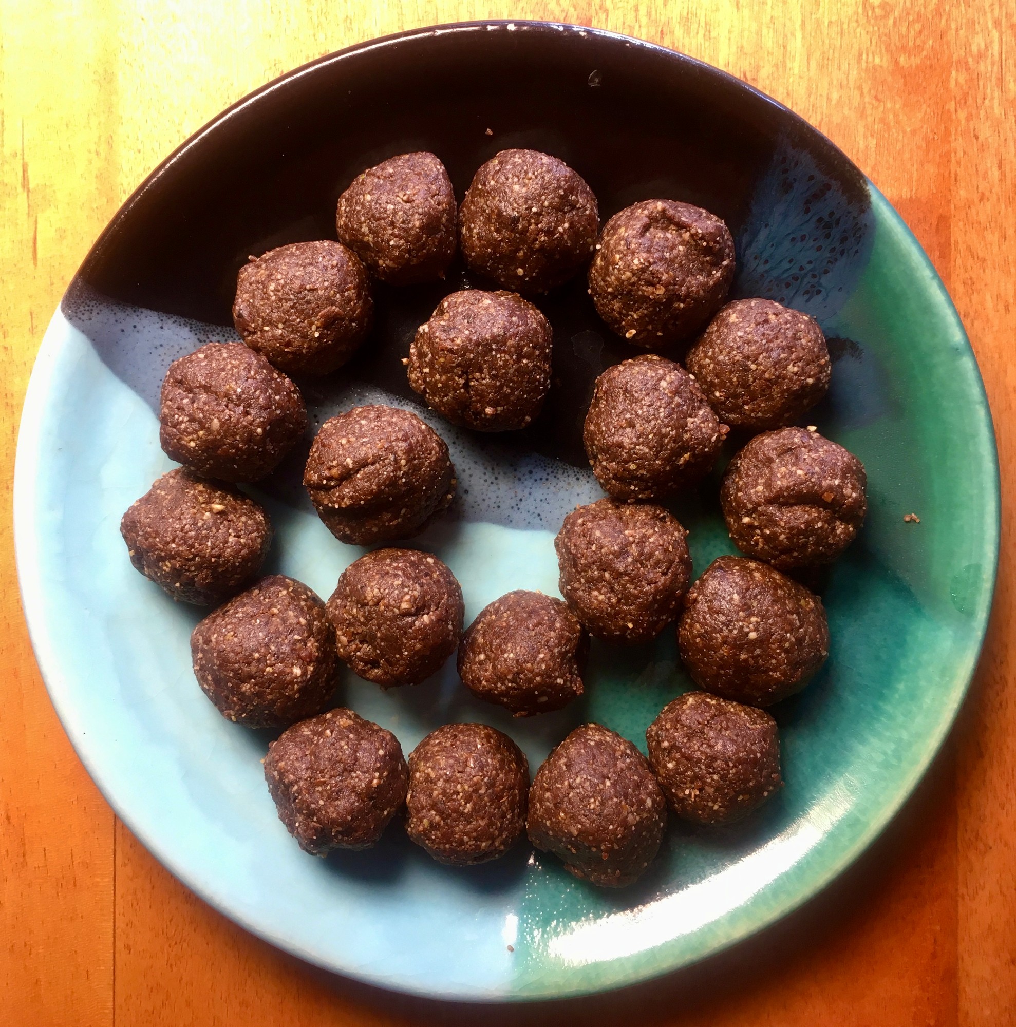 Bliss ball bites arranged in a circle on a teal and brown plate