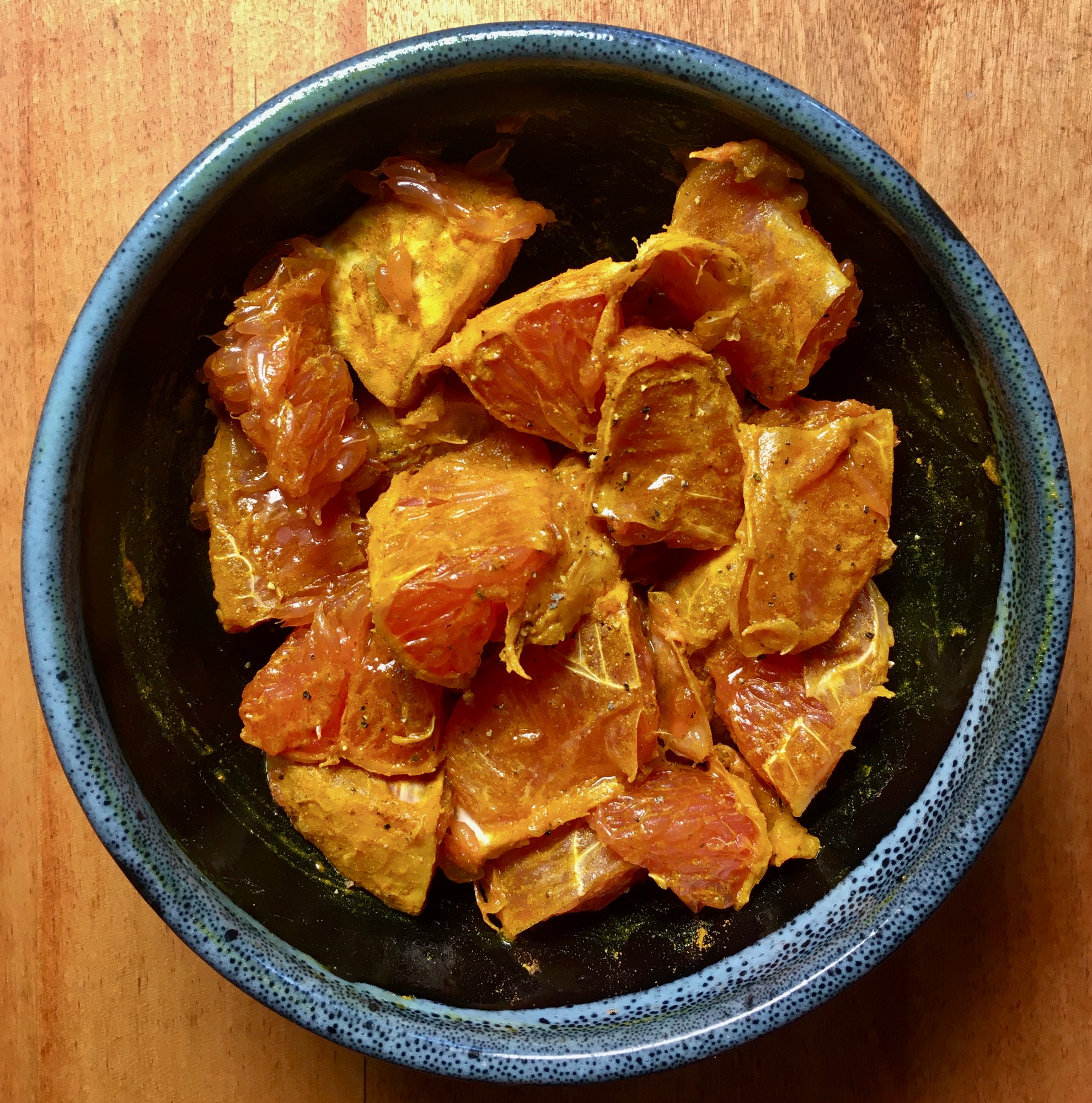 Grapefruit sections coated in turmeric and black pepper in a blue bowl