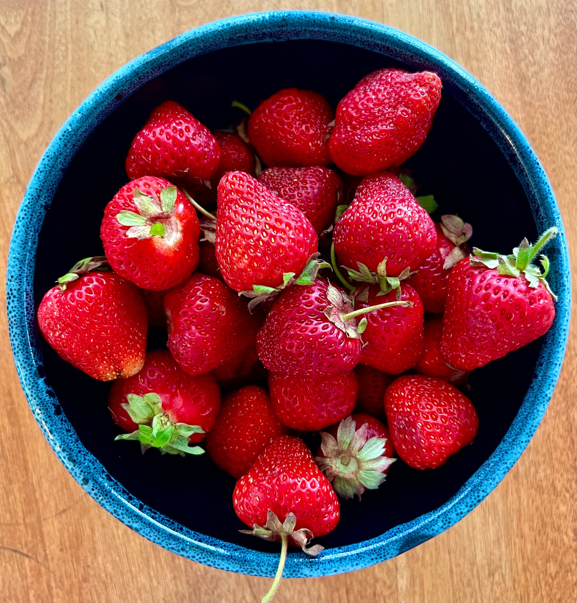 Fresh strawberries heaped in a blue bowl