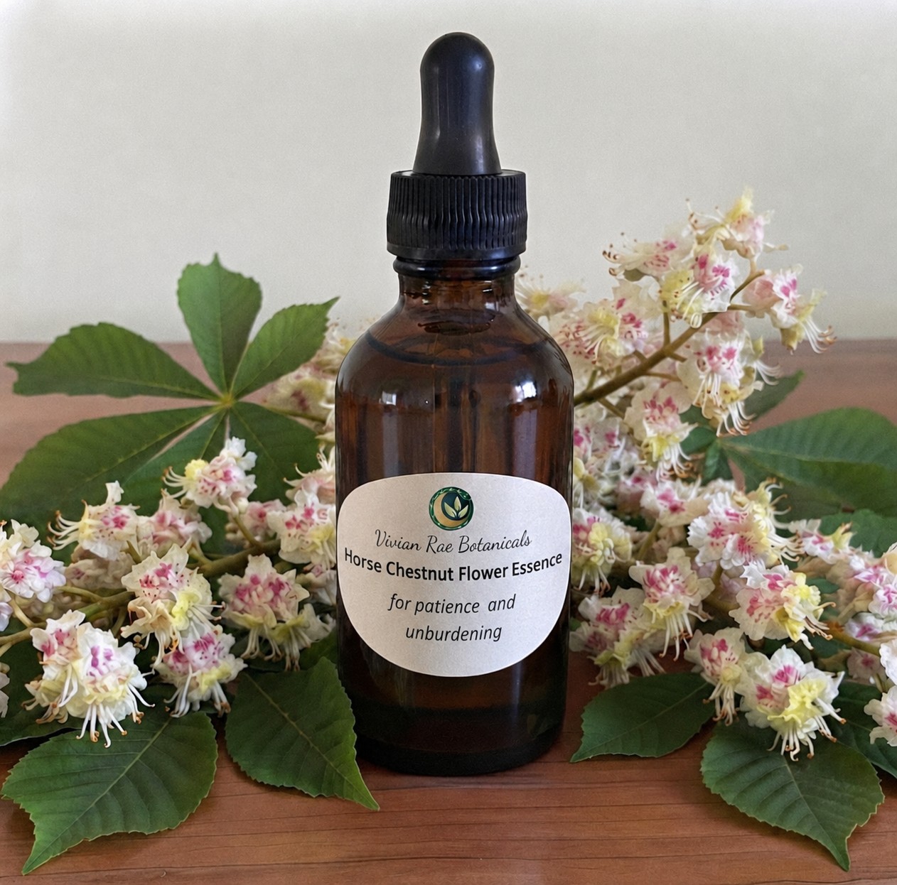 Bottle of Horse Chestnut Flower Essence among horse chestnut blossoms and leaves