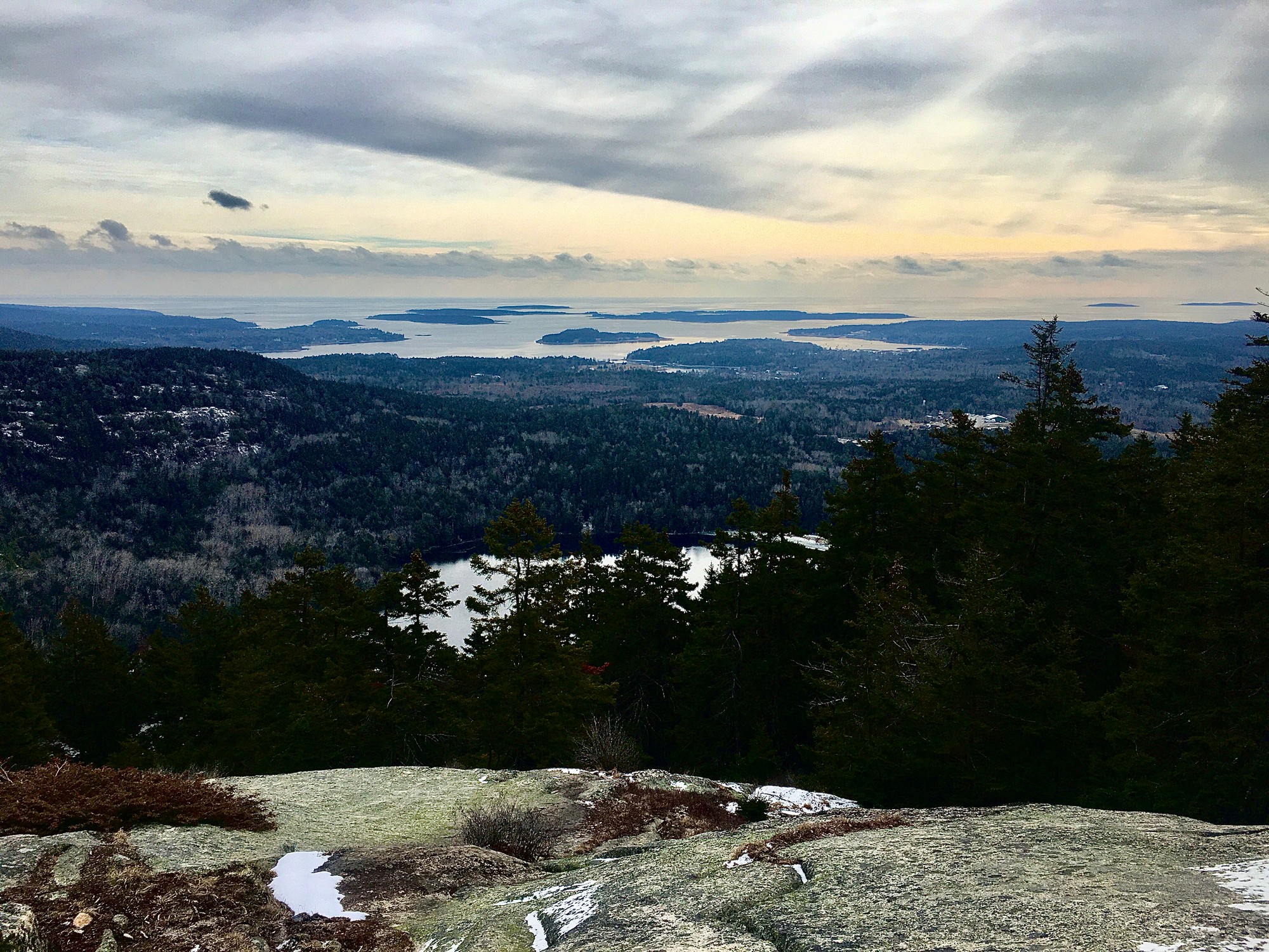 View from a granite summit over evergreen forest, a pond and islands at sea