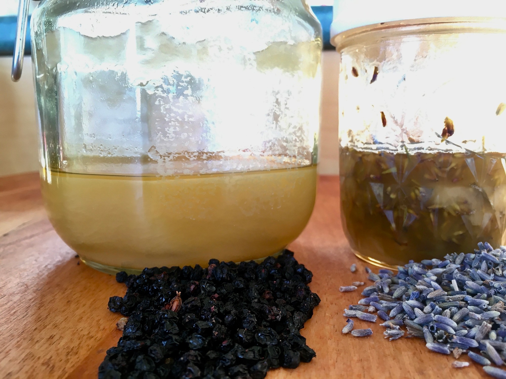 Jars of honey and lavender infusing beside dried elderberries and lavender buds