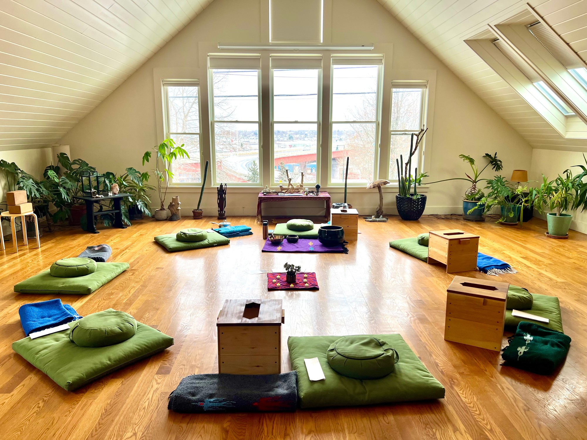 Sunlit studio with cushions and steam boxes circled around candles and singing bowls