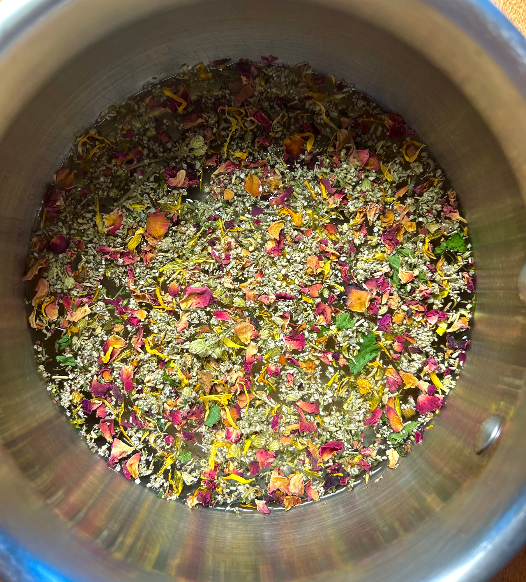 Dried rose petals and herbs floating in a pot of water