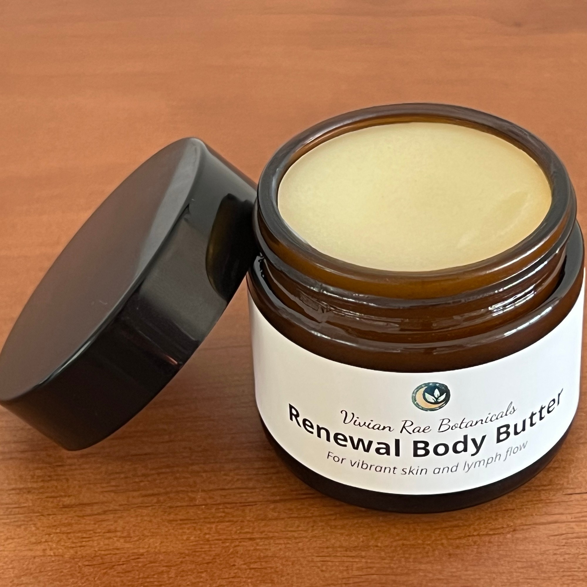 Open jar of Renewal Body Butter with its lid beside it