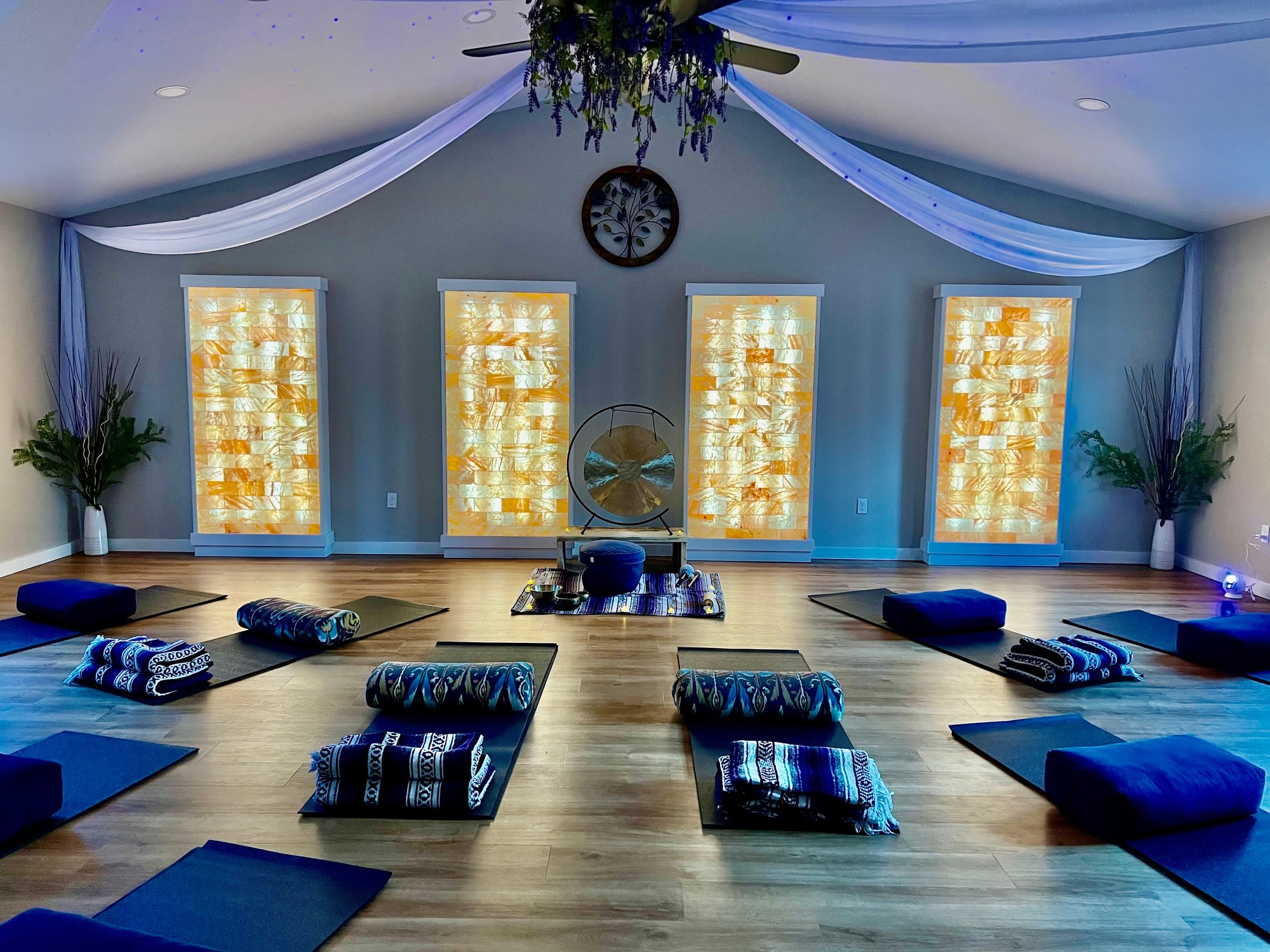 Mats, bolsters and blankets laid out facing a gong in a softly lit room