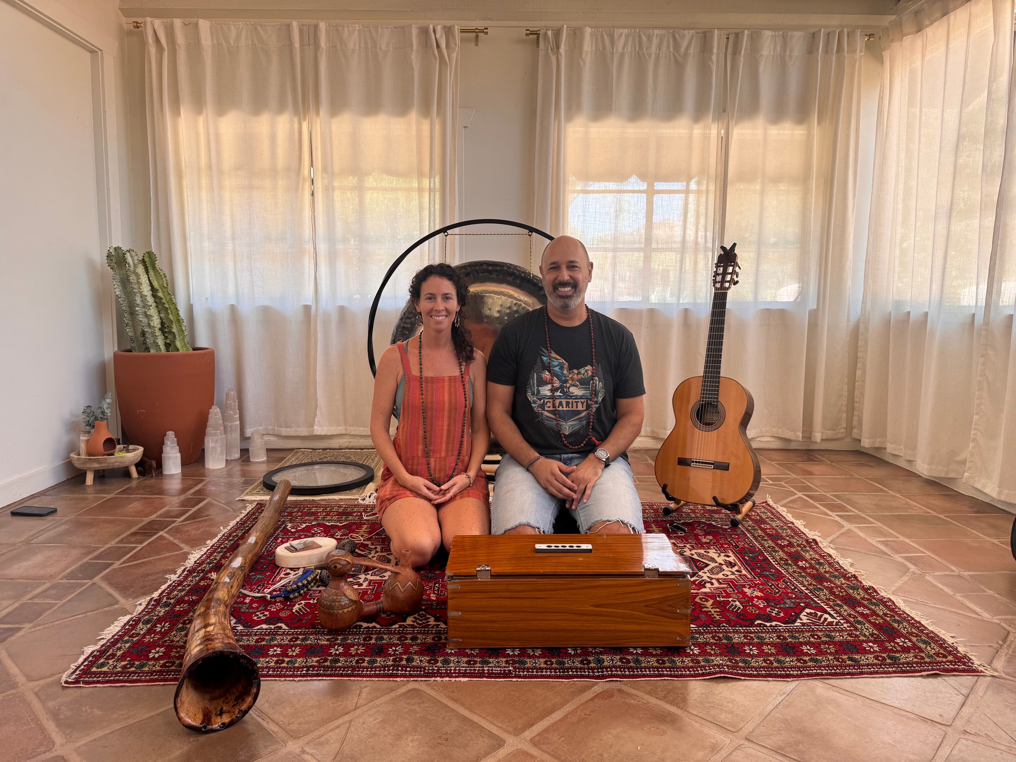 Vivian and Hamid Jabbar seated side by side before a gong, with a harmonium, a didgeridoo and a guitar