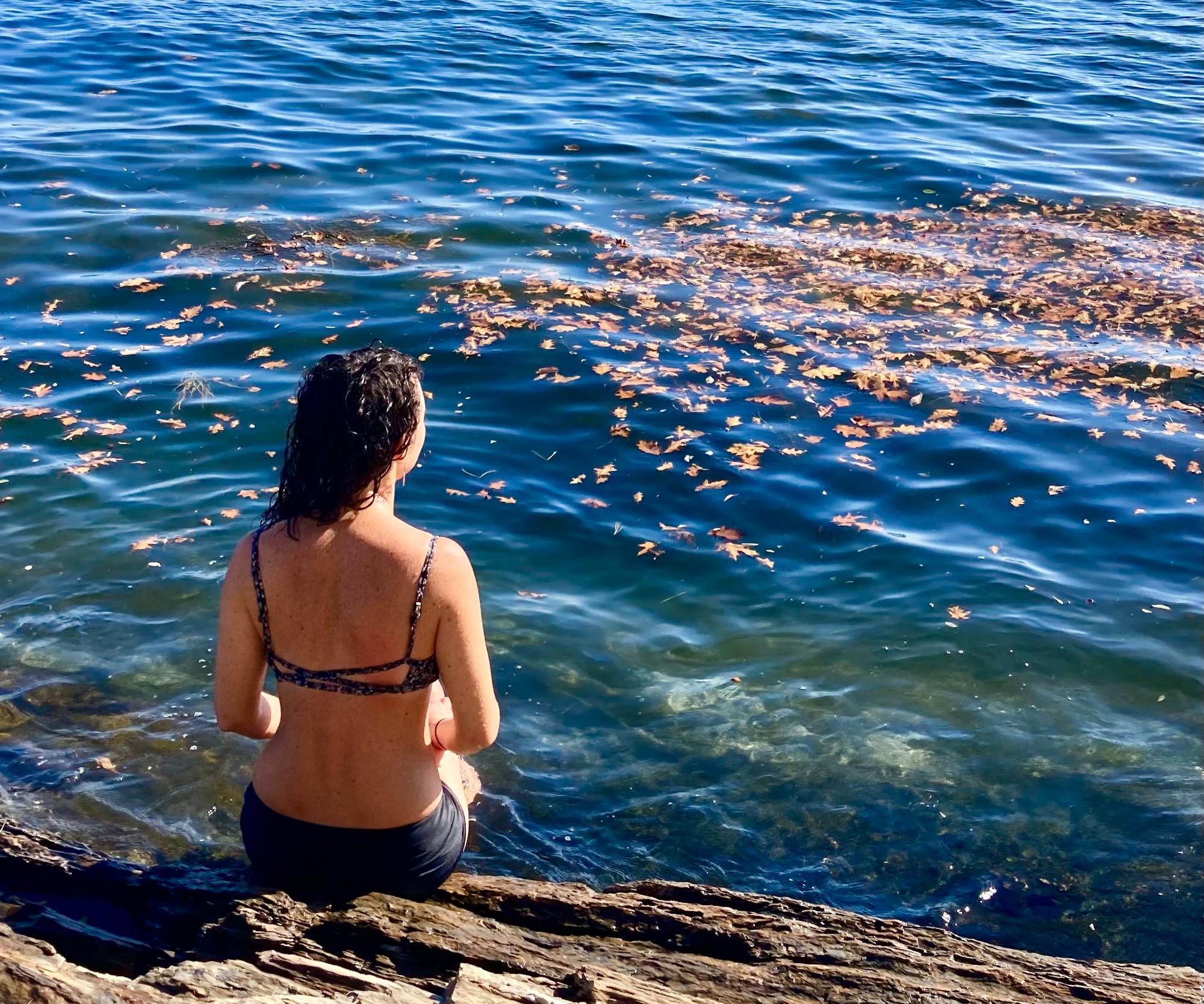 Vivian sitting on a rock ledge at the edge of clear water