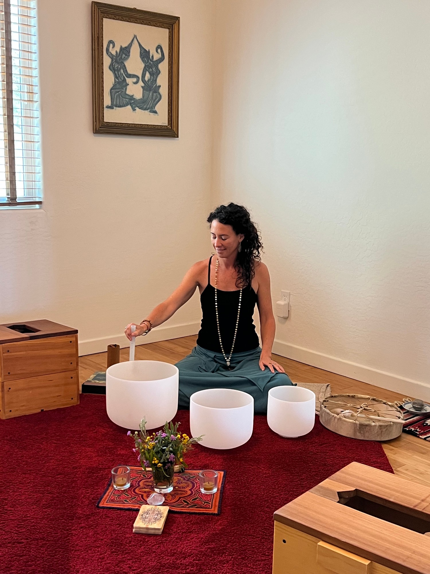 Vivian playing crystal singing bowls beside a drum and wooden steam boxes